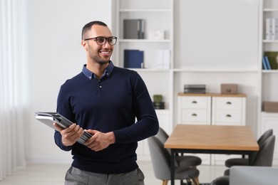 Smiling young businessman with folders in modern office. Space for text
