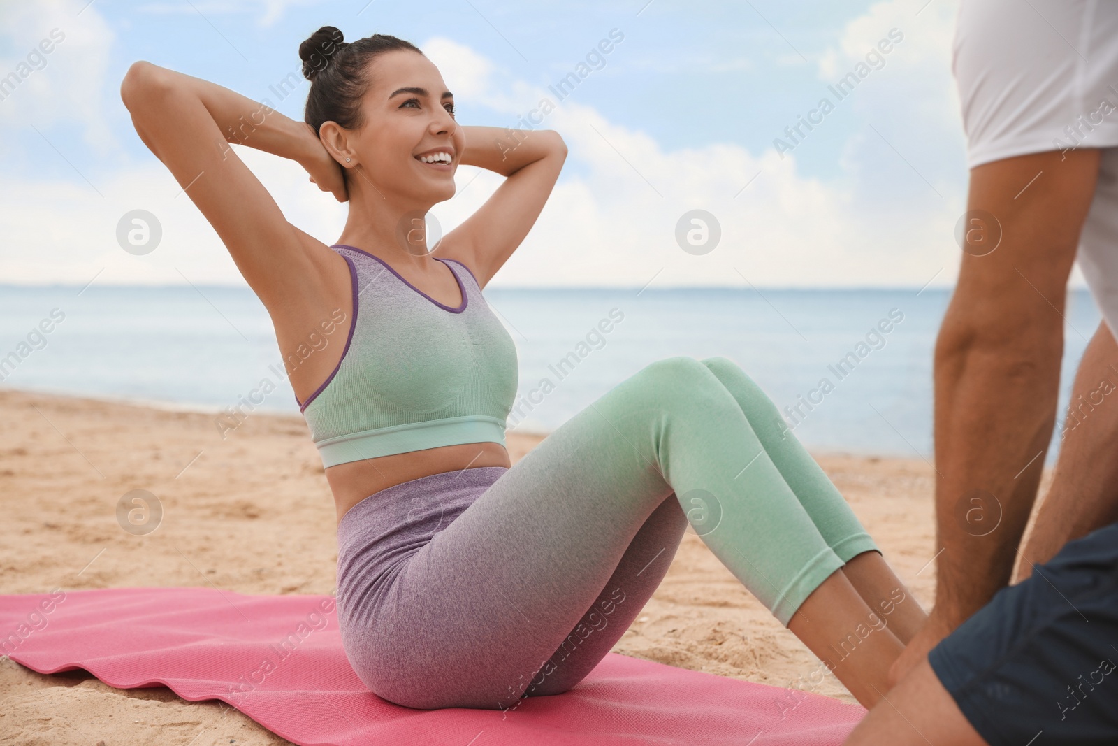 Photo of Couple doing exercise together on beach. Body training