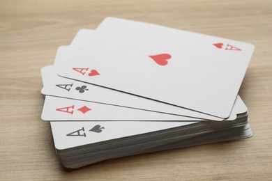 Photo of Four aces playing cards on wooden table, closeup