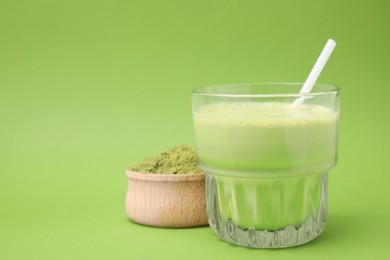 Glass of tasty matcha smoothie and powder on green background, closeup. Space for text