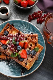 Photo of Delicious Belgian waffles with berries served on grey table, top view