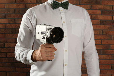 Man with vintage video camera near brick wall, closeup
