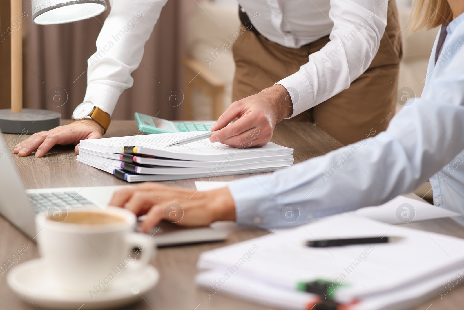 Photo of Businesspeople working with documents and using laptop at wooden table in office, closeup