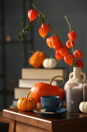 Beautiful autumn composition with cup of drink and pumpkins on wooden table indoors