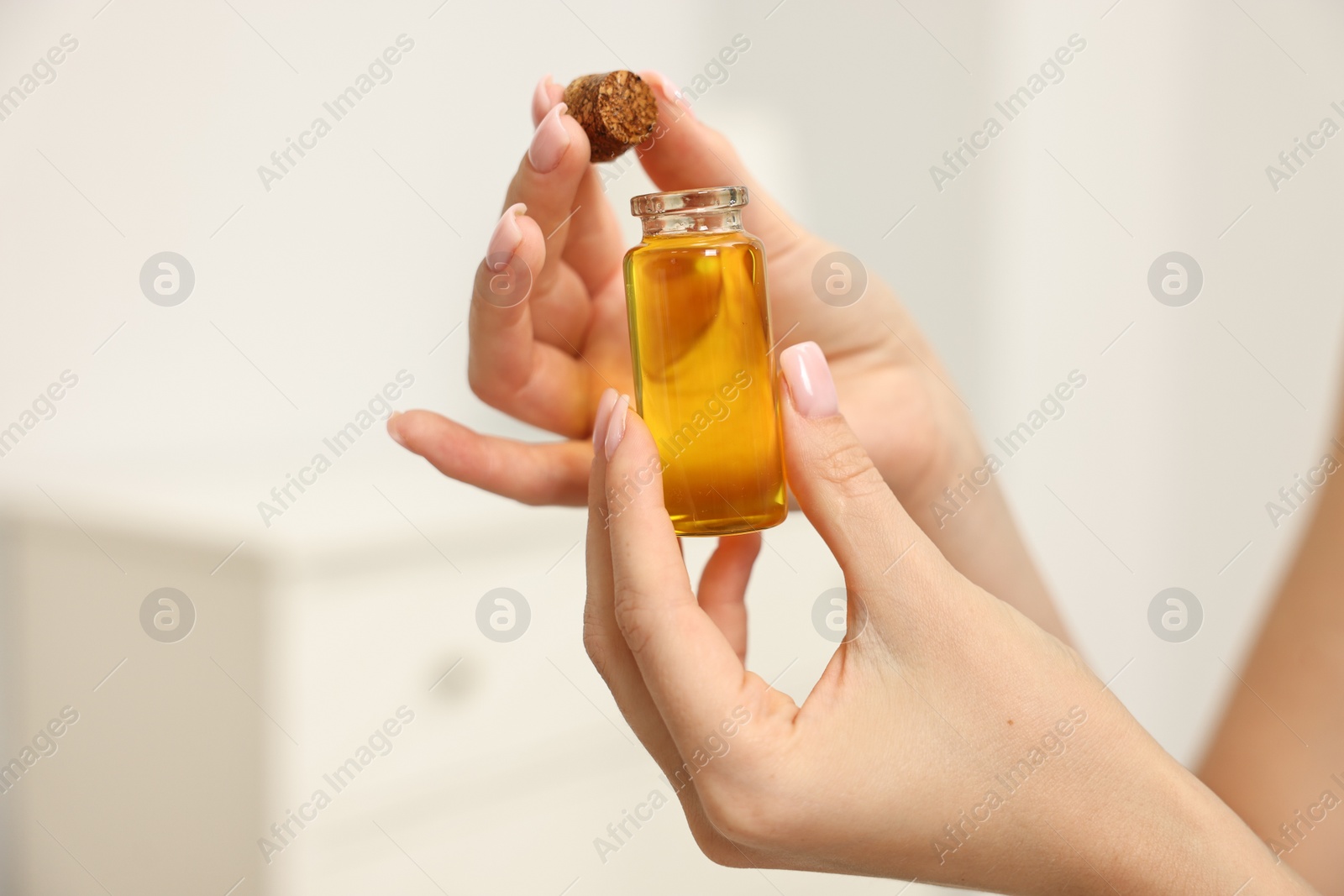 Photo of Aromatherapy. Woman with bottle of essential oil on light background, closeup