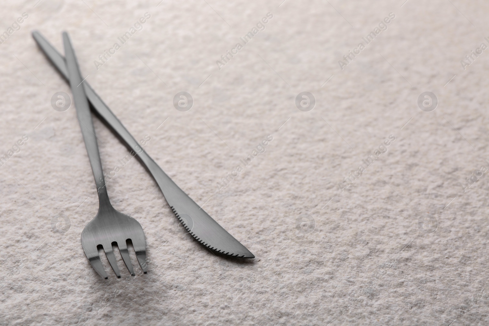 Photo of Stylish cutlery on beige textured table, closeup. Space for text