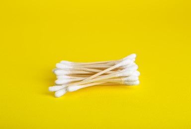 Many wooden cotton buds on yellow background