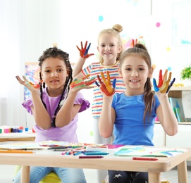 Photo of Cute little children showing painted hands at lesson indoors