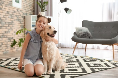 Photo of Cute little child with her pet on floor at home