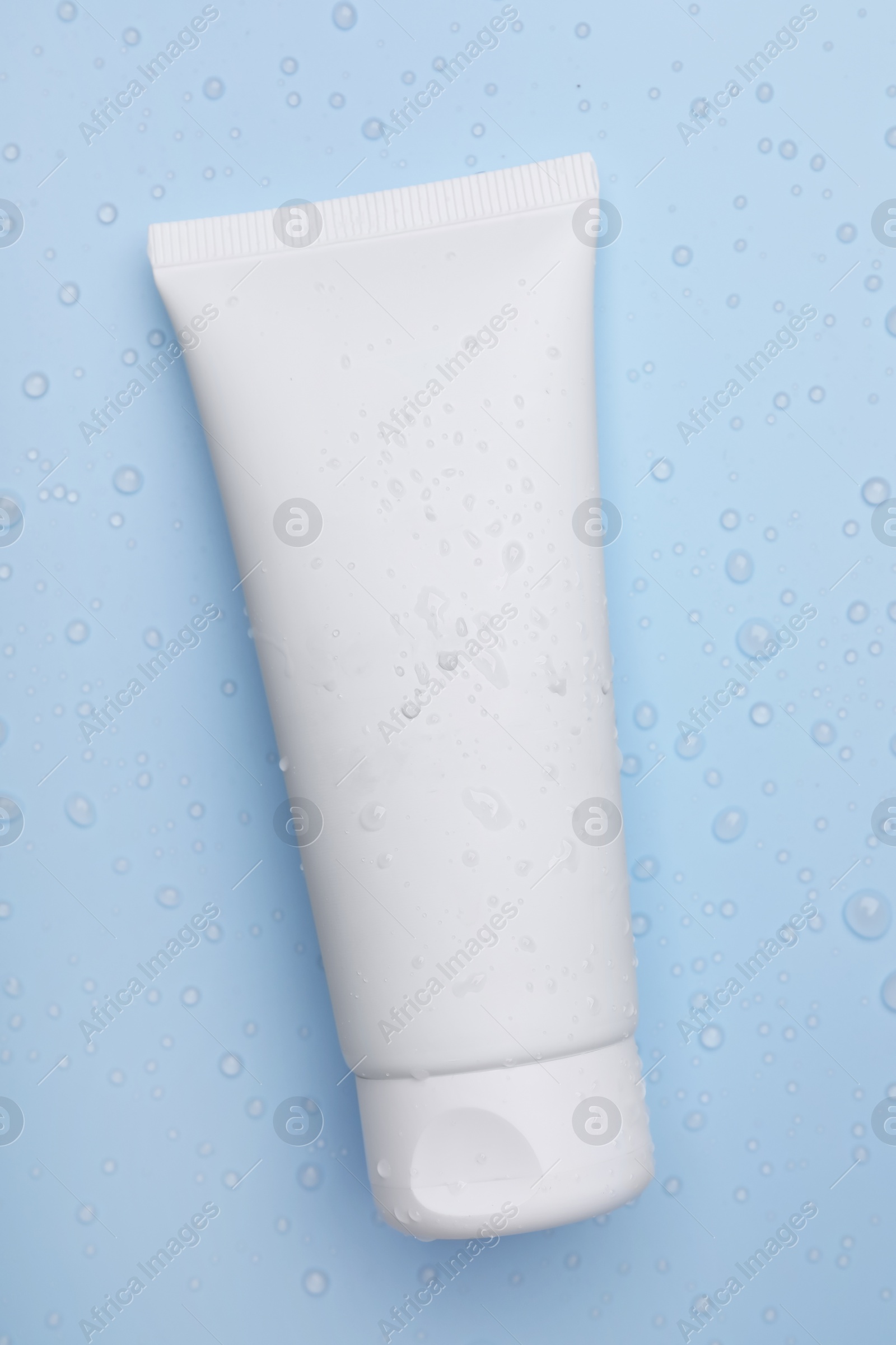 Photo of Wet tube of face cleansing product on light blue background, top view