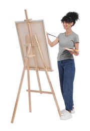 Photo of Young woman painting on easel with canvas against white background