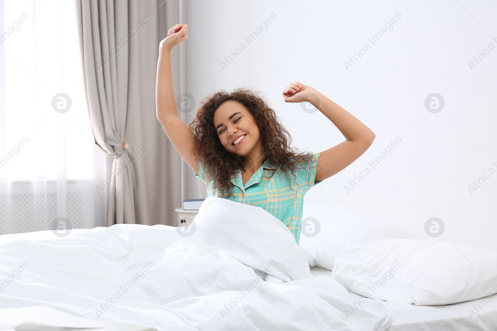 Photo of Young African-American woman stretching at home. Bedtime