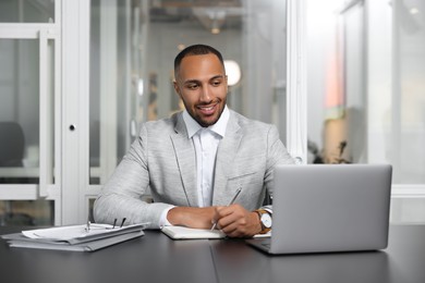 Photo of Happy man working at table in office. Lawyer, businessman, accountant or manager