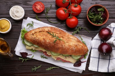 Delicious sandwich with tasty filling and ingredients on wooden table, flat lay