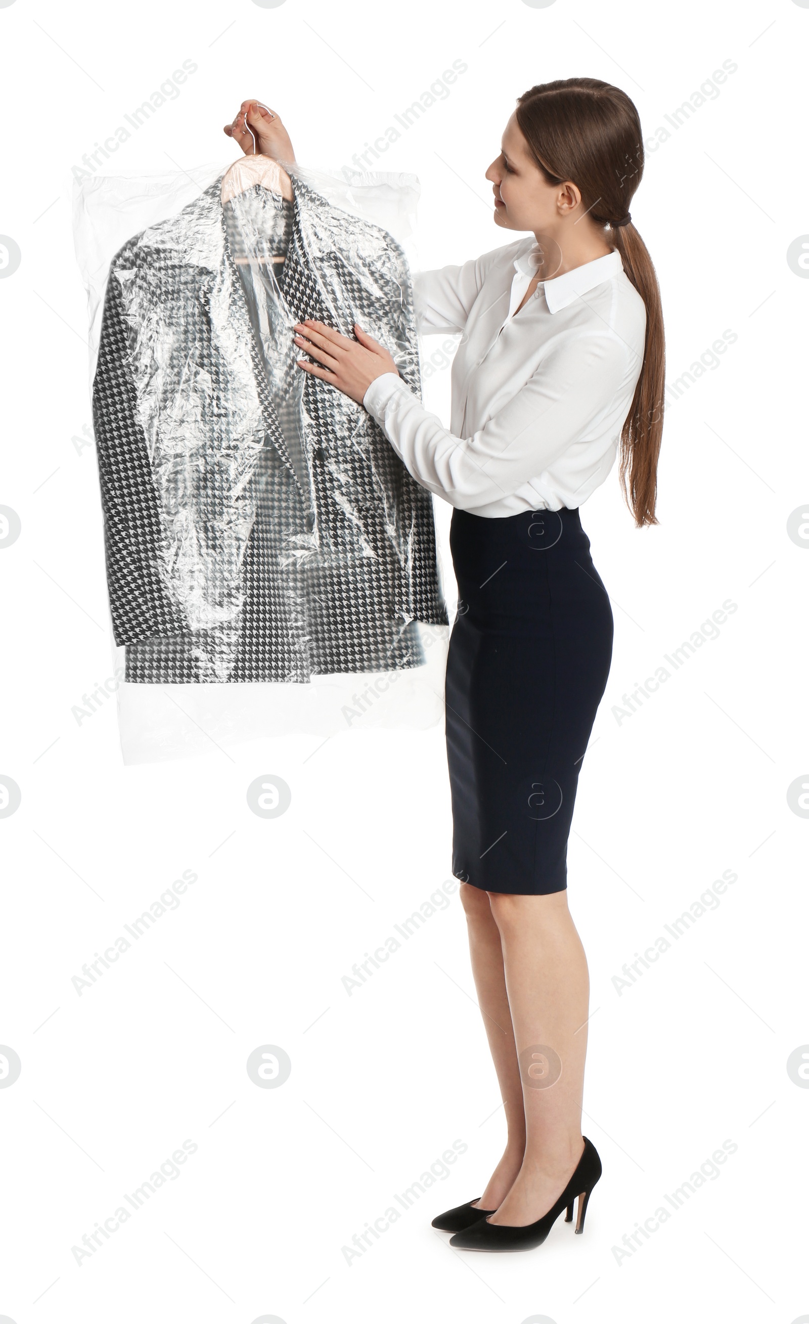 Photo of Young woman holding hanger with jacket in plastic bag on white background. Dry-cleaning service