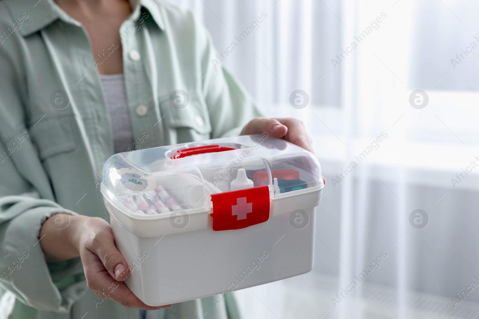 Photo of Woman holding first aid kit indoors, closeup. Space for text