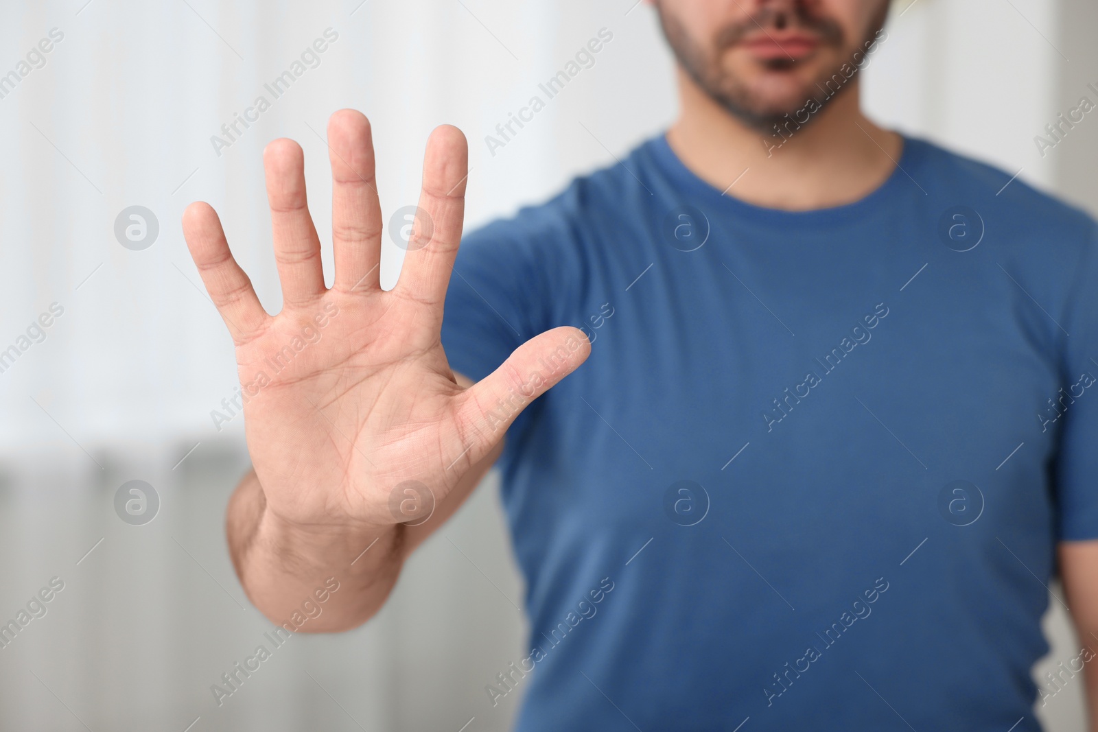 Photo of Man showing stop gesture indoors, closeup view