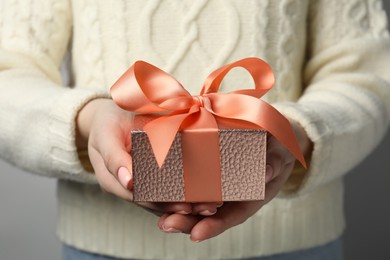 Photo of Christmas present. Woman holding gift box against grey background, closeup