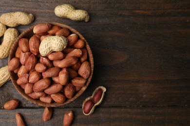 Photo of Fresh peanuts in bowl on wooden table, flat lay. Space for text