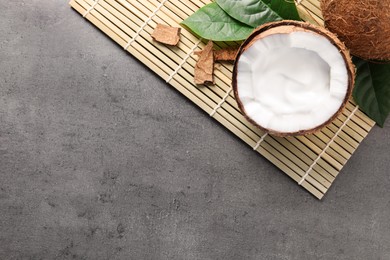 Photo of Ripe coconut with cream on grey table, flat lay. Space for text