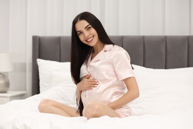 Photo of Happy pregnant woman on bed at home