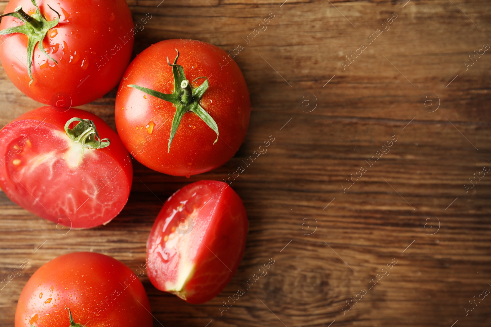 Photo of Fresh ripe tomatoes on wooden table, flat lay. Space for text