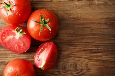 Photo of Fresh ripe tomatoes on wooden table, flat lay. Space for text