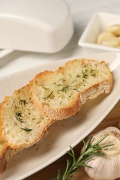 Photo of Tasty baguette with garlic, rosemary and dill on table, closeup