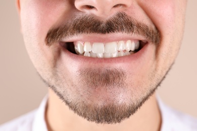 Young man with healthy teeth smiling on color background, closeup