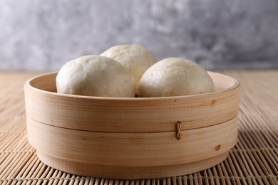 Photo of Delicious Chinese steamed buns on bamboo mat, closeup