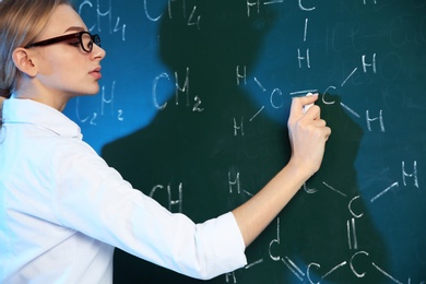 Female scientist writing chemical formula on chalkboard