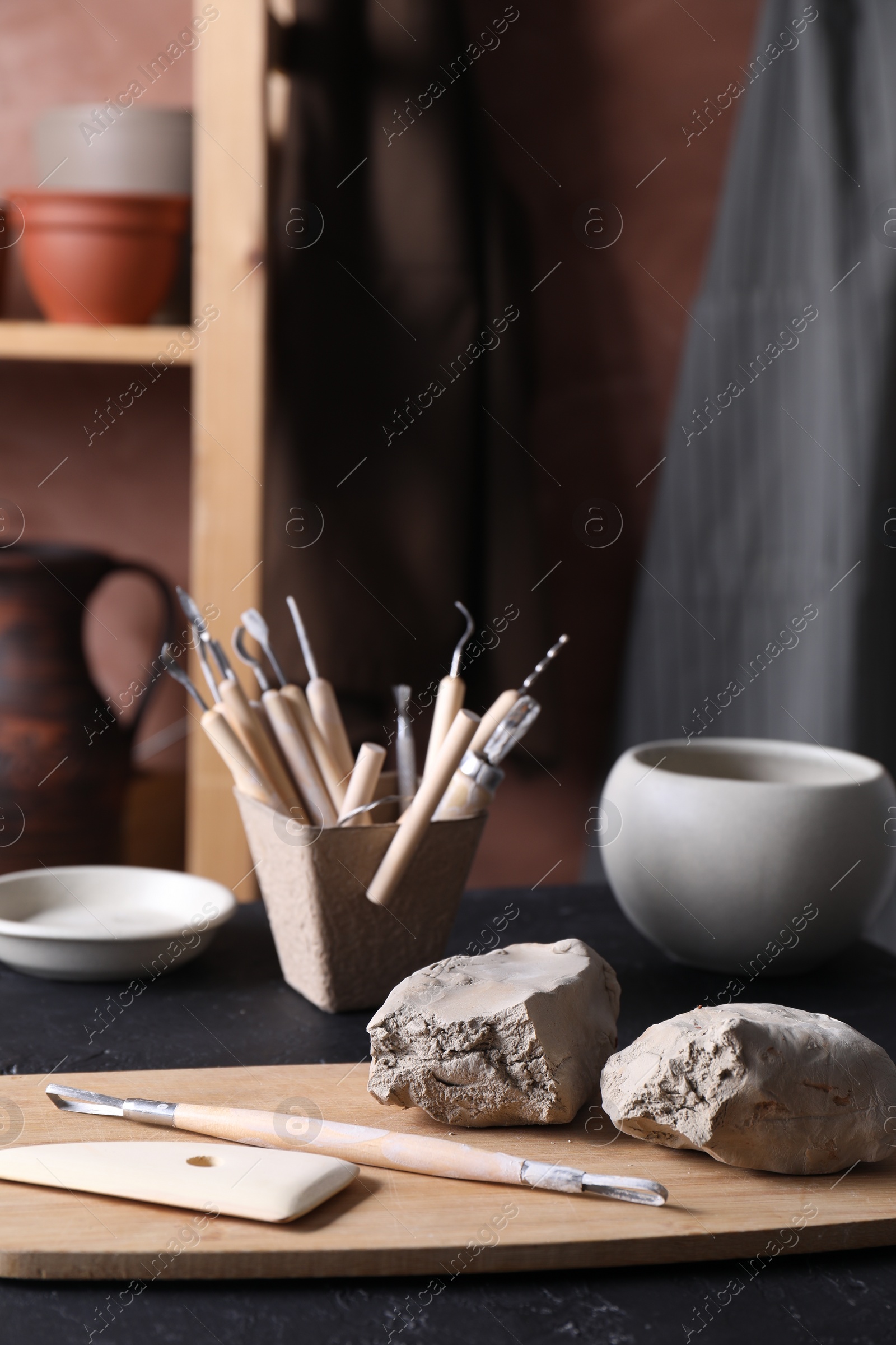 Photo of Clay and set of modeling tools on table in workshop