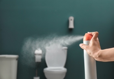 Photo of Woman spraying air freshener in bathroom