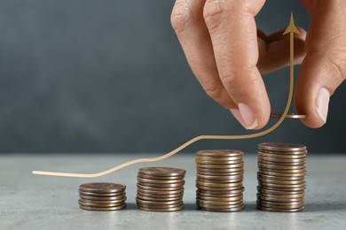 Image of Salary increase concept. Woman stacking coins on grey table and illustration of up arrow