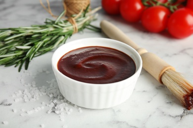 Photo of Composition with bowl of barbecue sauce on marble background