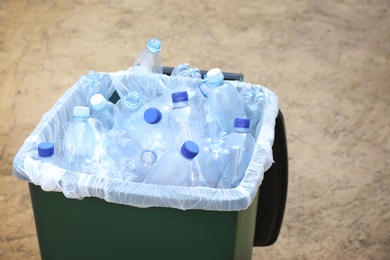 Photo of Many used plastic bottles in trash bin outdoors, closeup. Recycling problem