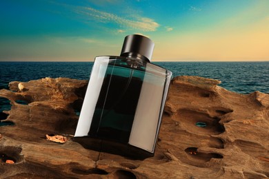 Image of Bottle of woody aquatic perfume on tree bark near ocean. Fresh scent