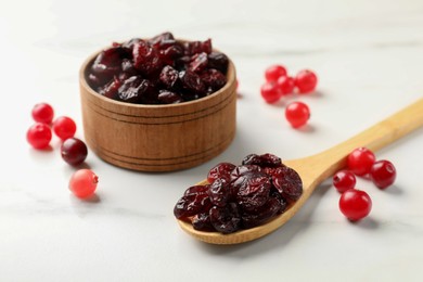 Tasty dried cranberries and fresh ones on white table, closeup