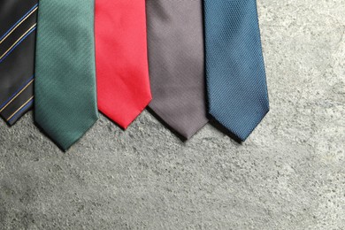 Photo of Different neckties on grey textured background, flat lay. Space for text