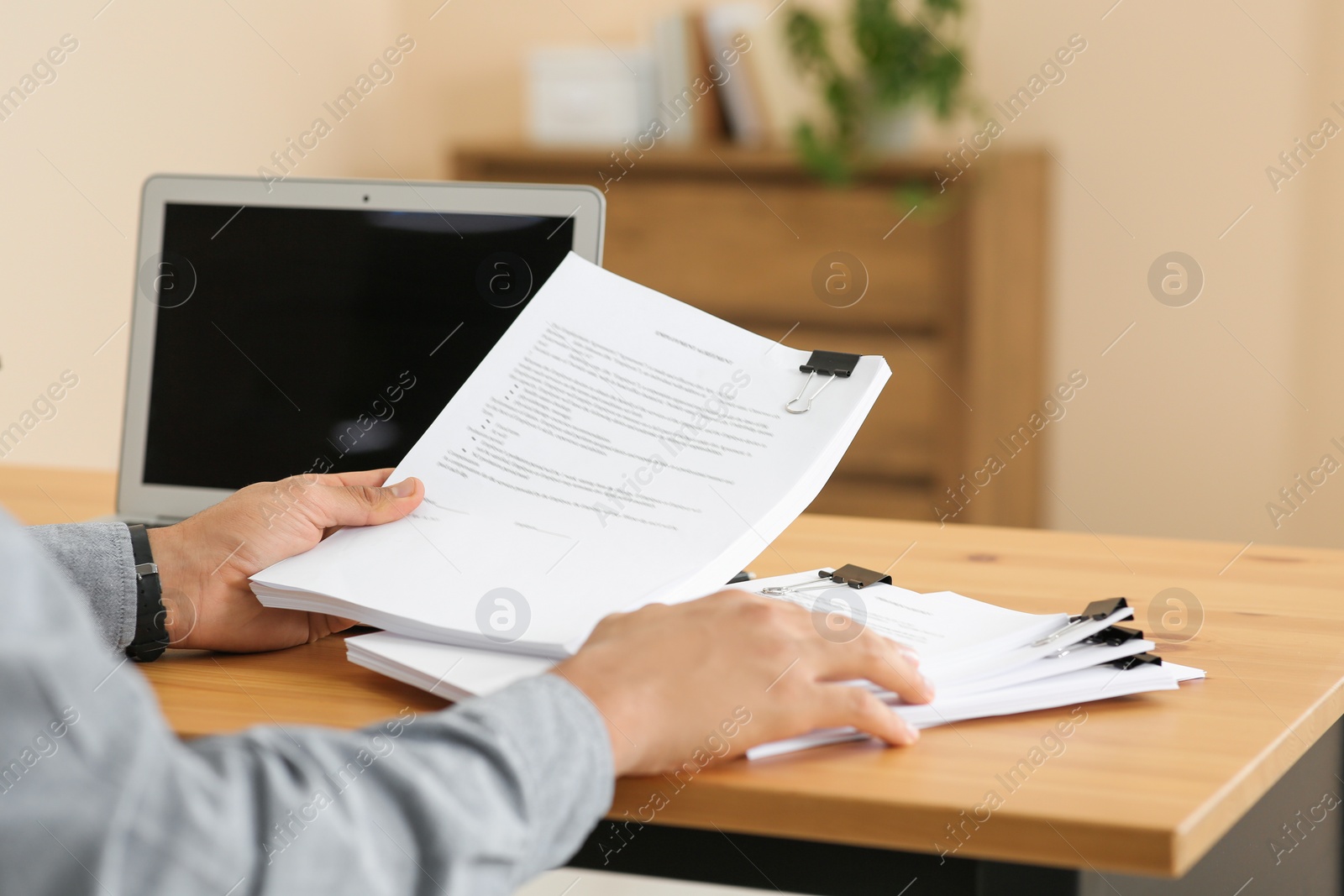 Photo of Man working with documents at wooden table in office, closeup