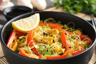 Photo of Stir-fry. Delicious cooked noodles with chicken and vegetables in bowl on table, closeup