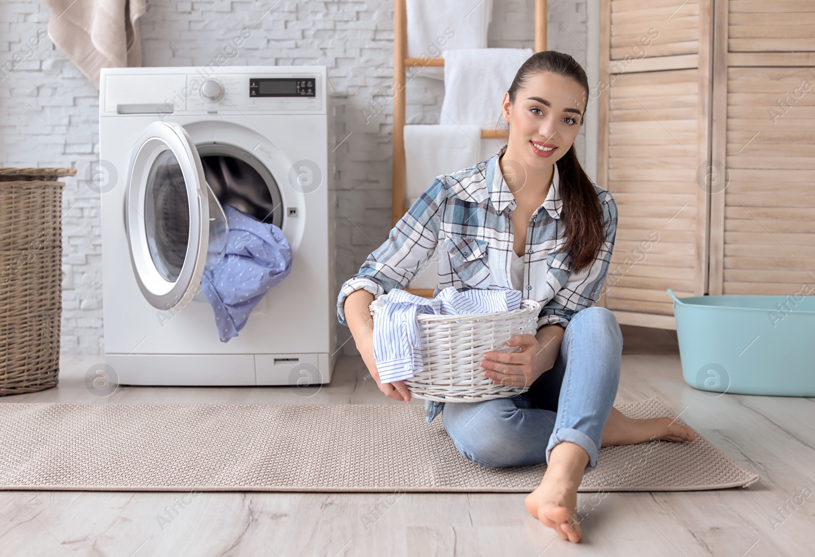 Photo of Young woman with laundry basket at home