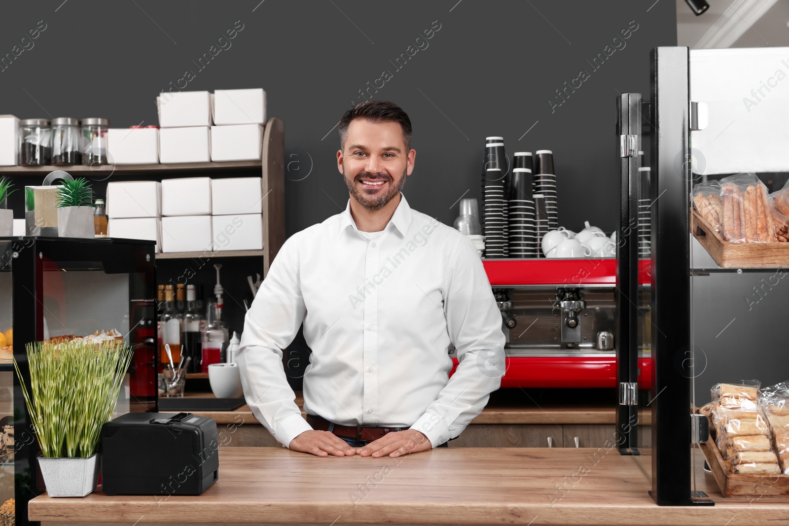 Photo of Portrait of happy business owner at desk in his cafe
