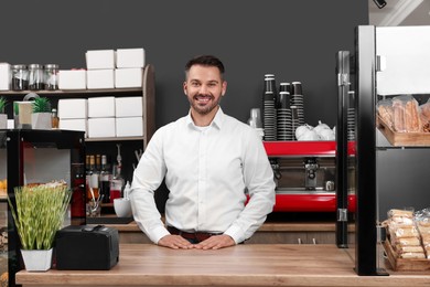 Photo of Portrait of happy business owner at desk in his cafe
