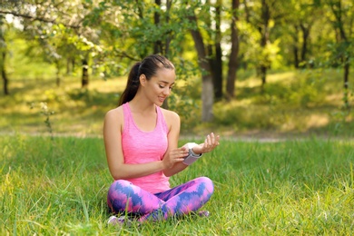 Young woman checking pulse outdoors on sunny day