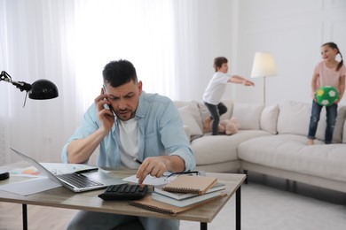 Photo of Overwhelmed man combining parenting and work at home