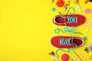 Shoes tied together and decor on yellow background, flat lay with space for text. April Fool's Day