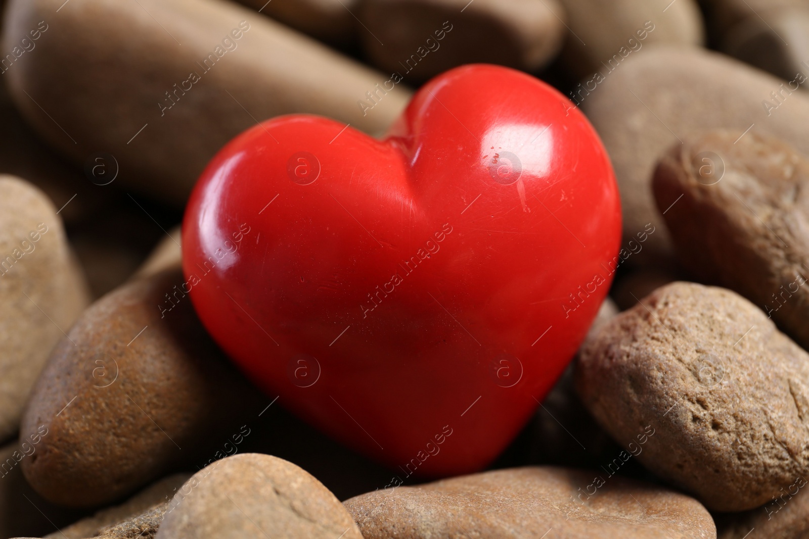 Photo of One red decorative heart on stones, closeup