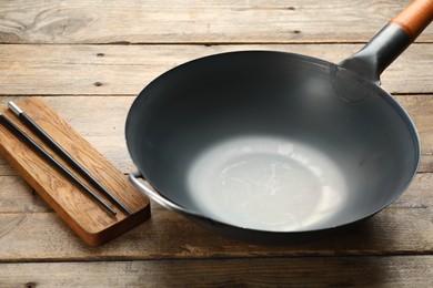 Photo of Empty iron wok with chopsticks on wooden table