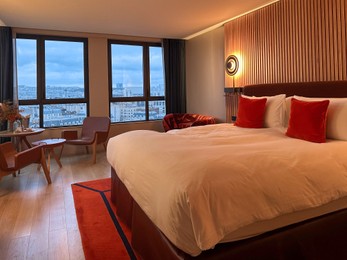 Photo of Stylish hotel room interior with large bed, lamp and table